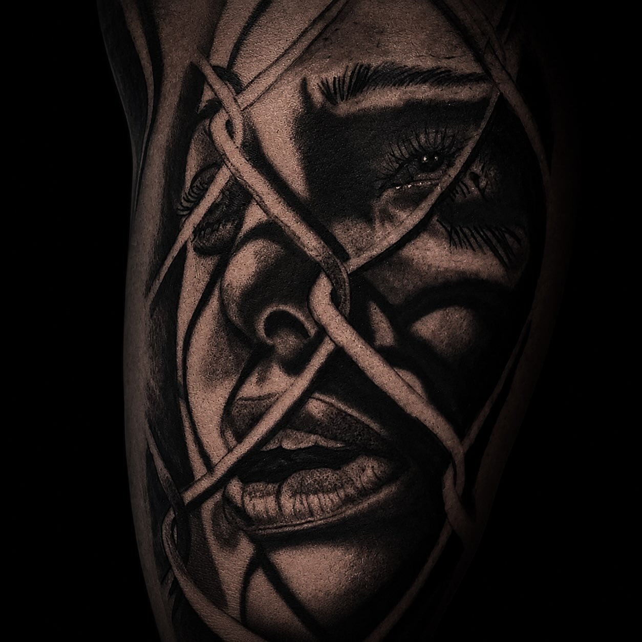 Black and grey realism tattoo portrait of a woman's face wrapped in chains
